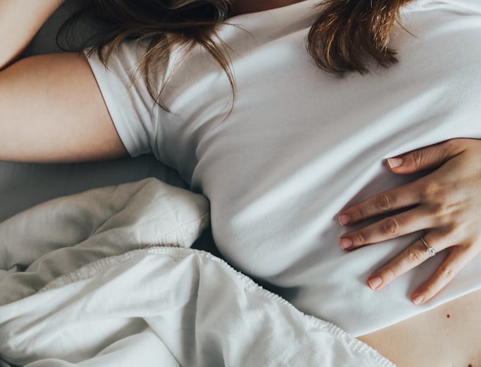 Frau im Bett mit Bauchschmerzen