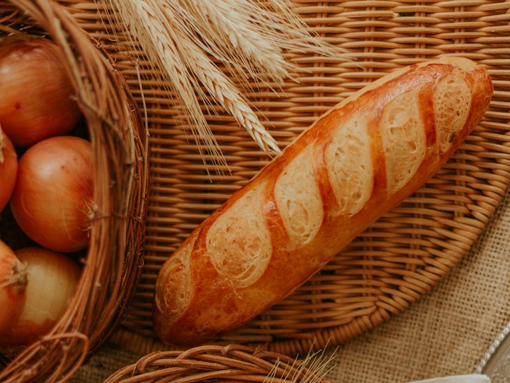 Baguette neben Zwiebeln und Getreideähren